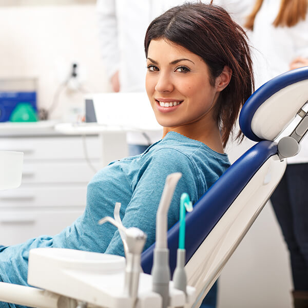A young woman sitting in the dentist's chair while smiling
