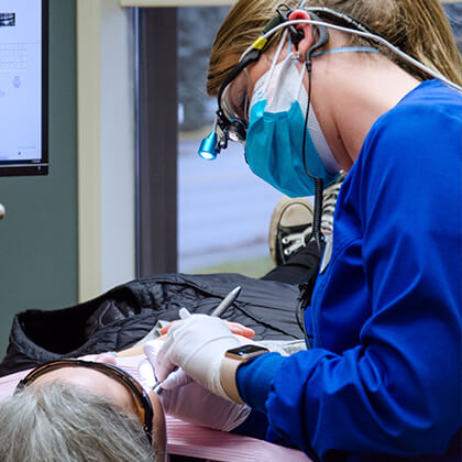 Dr. Wilson conducting a dental exam on an older woman who is lying down